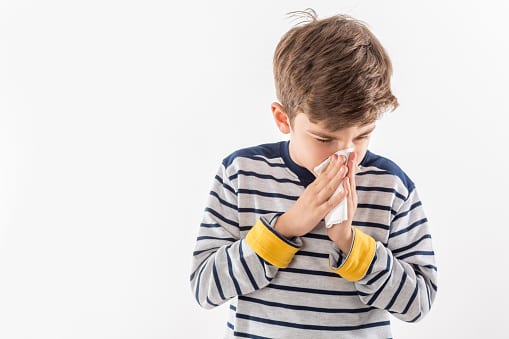 child with flu blowing nose
